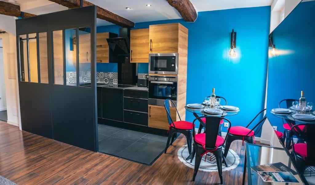 une cuisine avec des murs bleus et une table avec des chaises rouges dans l'établissement Appartement climatisé, plein centre, Garage, à Sainte-Maxime