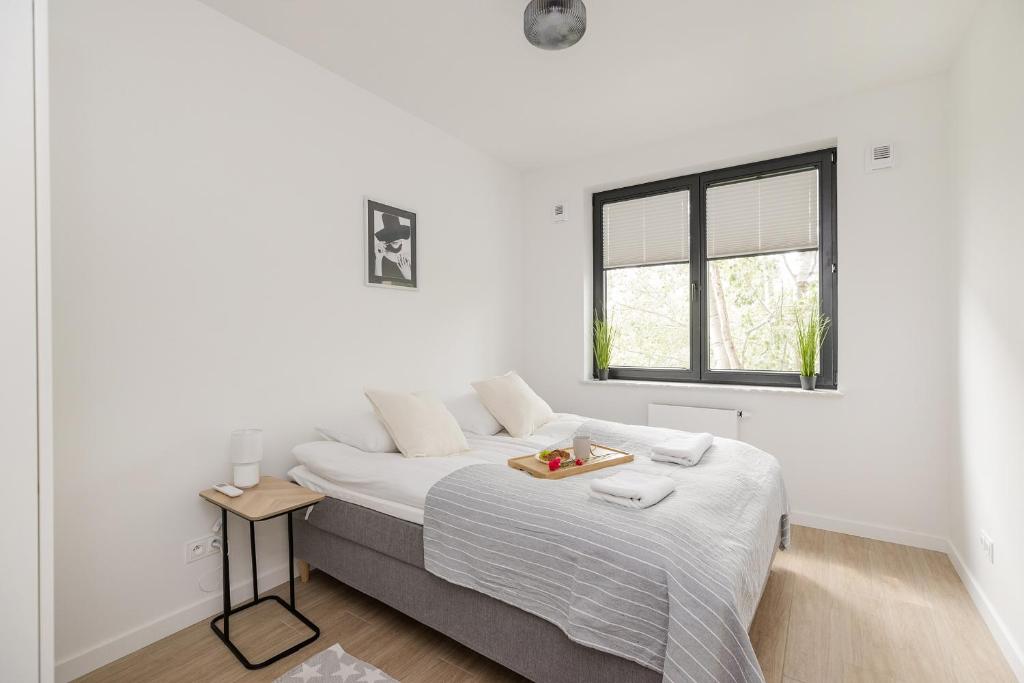 a white bedroom with a bed with a tray of fruit on it at ShortStayPoland Sokratesa in Warsaw