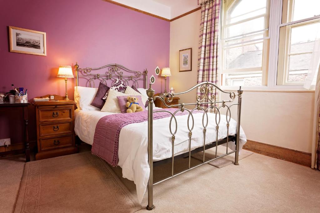 a bedroom with a bed with purple walls and a window at Roscrea Bed & Breakfast in Bodmin