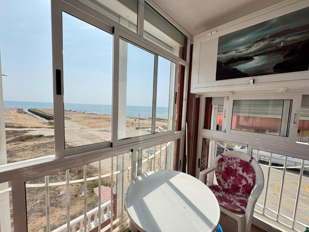 a balcony with a table and chairs and the ocean at Beachfront apartment in La Mata in La Mata