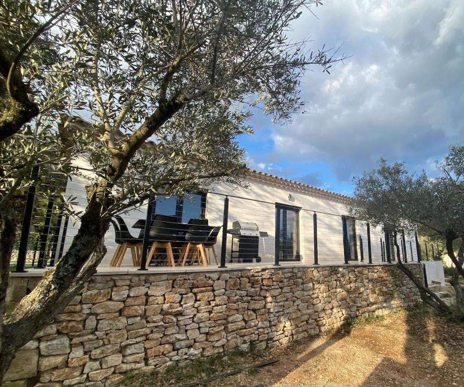 une maison avec deux chaises et un mur en pierre dans l'établissement Charmante maison à Garrigues St-Eulalie, à Collorgues