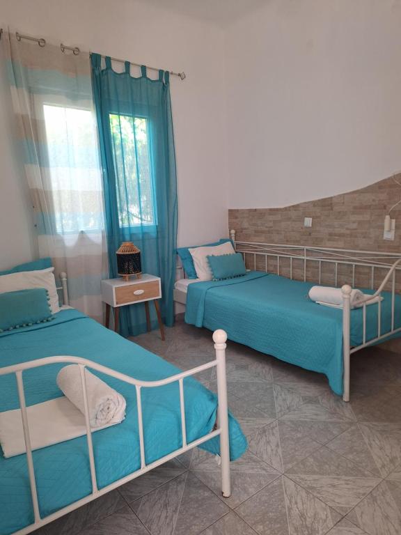 two beds in a room with blue curtains at Vithos in Agnontas