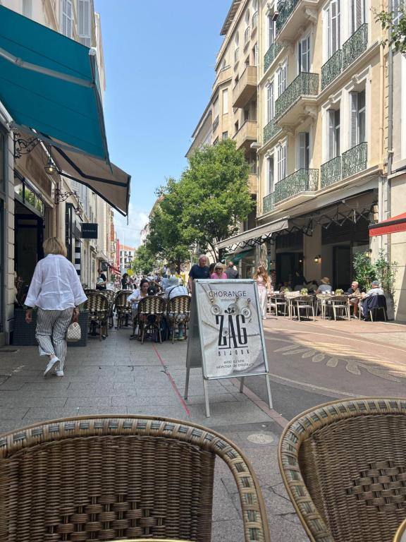 un panneau dans une rue avec des personnes assises à table dans l'établissement Entire studio Cannes Raphael, à Cannes