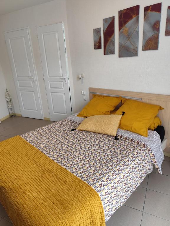 une chambre avec un lit avec des oreillers jaunes dans l'établissement Studio de L'Estuaire, à Saint-Seurin-de-Cursac