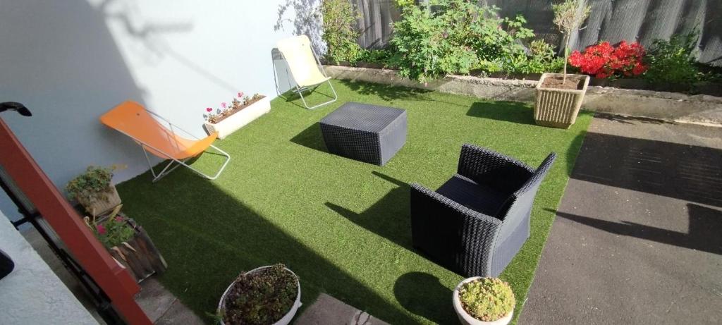 un jardin miniature avec des chaises, de l'herbe et des plantes dans l'établissement Villa Mon Repos 2, à La Bourboule