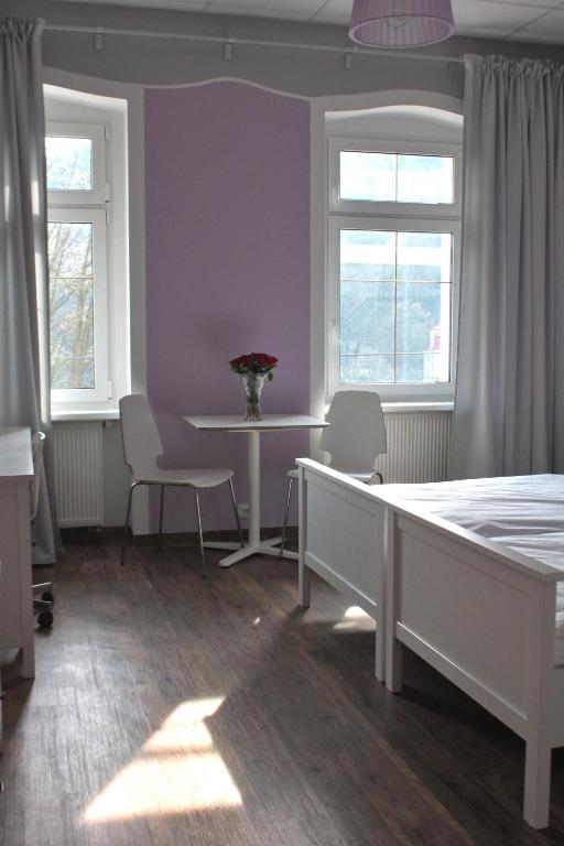 a bedroom with a bed and a table and two windows at Hotel Orix in Jáchymov
