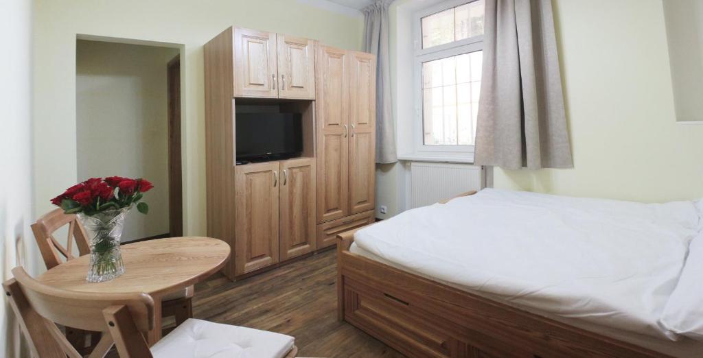 a small bedroom with a bed and a table with a vase of flowers at Hotel Orix in Jáchymov