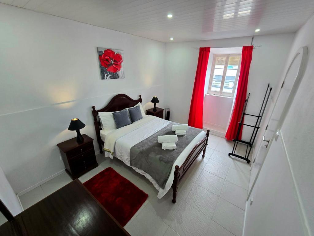 a bedroom with a bed and a window with red curtains at The Cedar Tree House in Sete Cidades