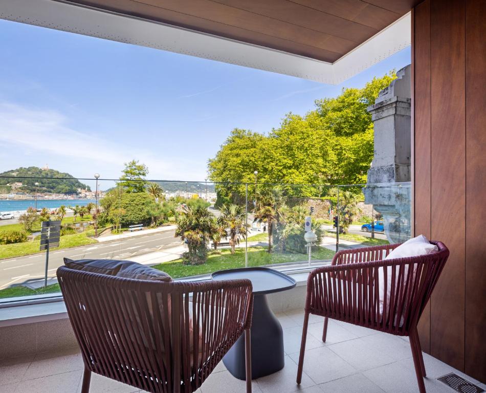 Pokój z dużym oknem ze stołem i krzesłami w obiekcie Palacio Miramar by FeelFree Rentals w mieście San Sebastián