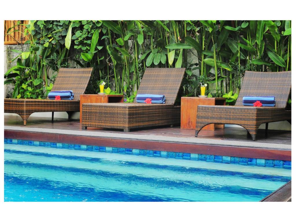 a group of benches sitting next to a swimming pool at Arana Suite in Legian