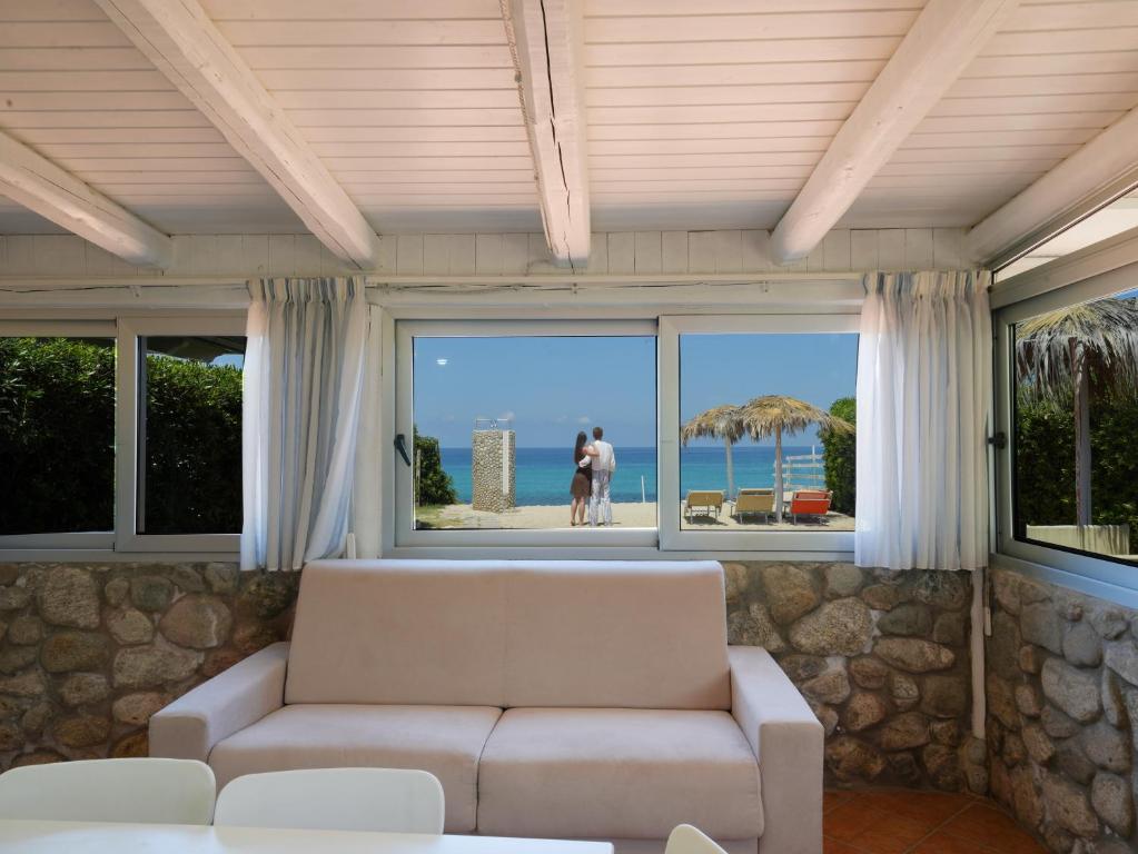 a living room with a couch and a large window at Marinella Beach Apartments - On The Beach - Private Free Parking in Capo Vaticano
