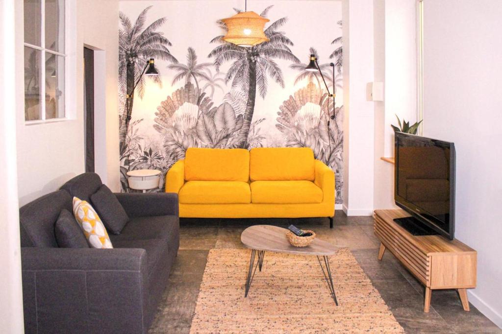 a living room with a yellow couch and a tv at Au Coeur du marché - Hyper centre Dijon - Terrasse in Dijon