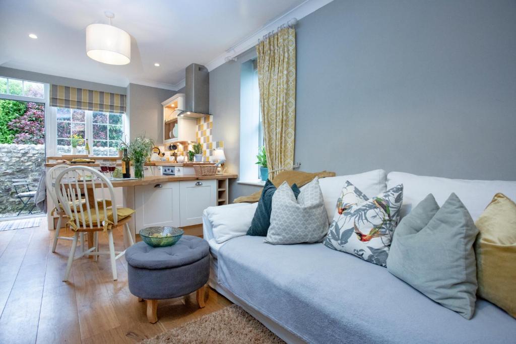 a living room with a blue couch and a kitchen at Dairy Cottage in Seaton
