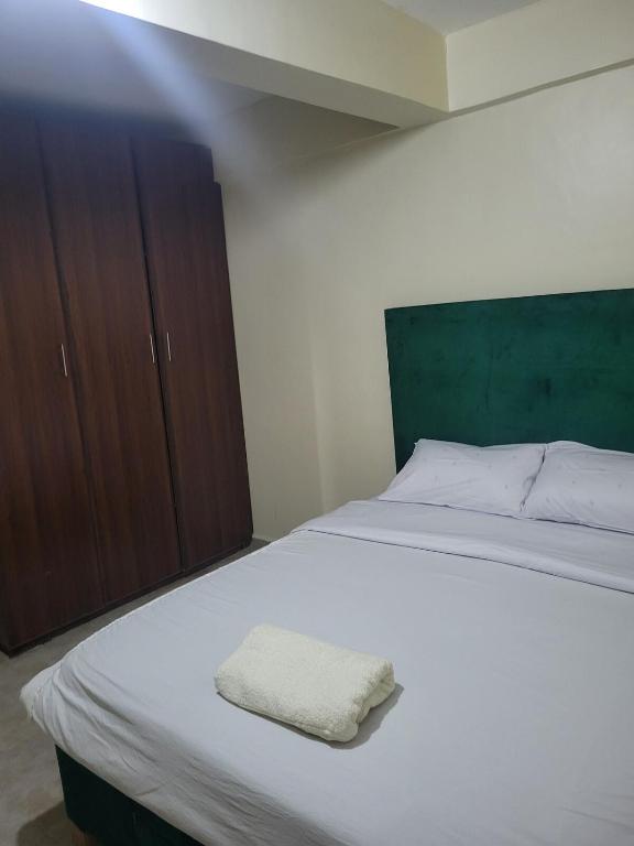a bedroom with a white bed and wooden cabinets at Baylynn Homes in Homa Bay