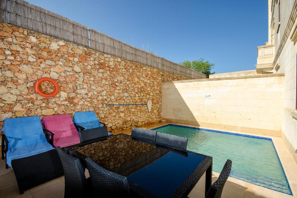 a patio with a table and chairs next to a swimming pool at Girgentina in Xagħra