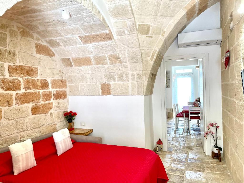 a bedroom with a red bed in a stone wall at Antica Pietra in Polignano a Mare