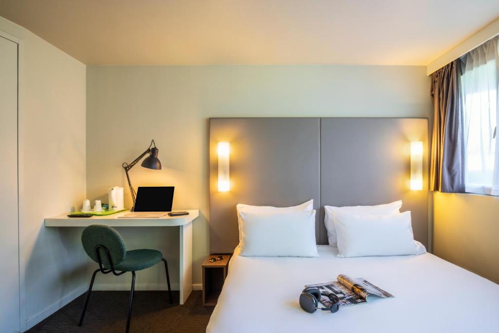 a hotel room with a bed with a desk and a laptop at Campanile Nîmes Sud - Caissargues in Caissargues