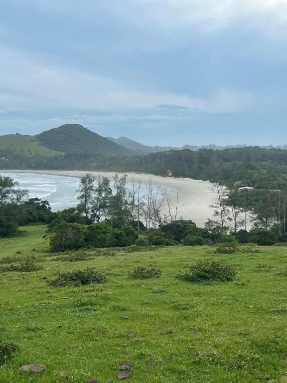 a green field with a view of a beach at Morada do rosa ouvidor in Garopaba