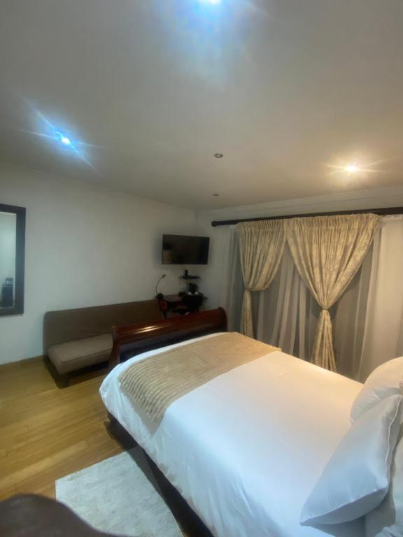 a bedroom with a large white bed and a couch at Blvckstylr in Cape Town