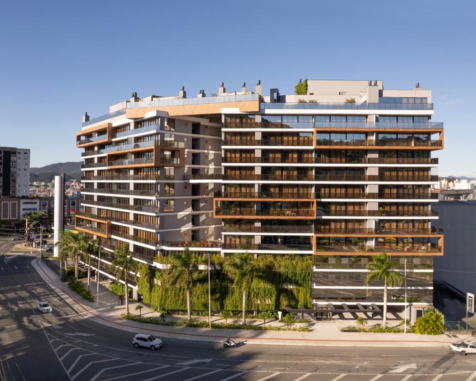 a tall building with palm trees in front of a street at The Spot One by Viva - Luxo e acesso direto ao Balneário Shopping in Balneário Camboriú