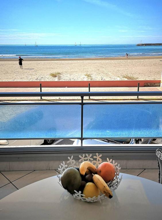 - un bol de fruits sur une table en face d'une plage dans l'établissement Première ligne mer Appartement t2 cabine pour 4 personnes N123, à Palavas-les-Flots