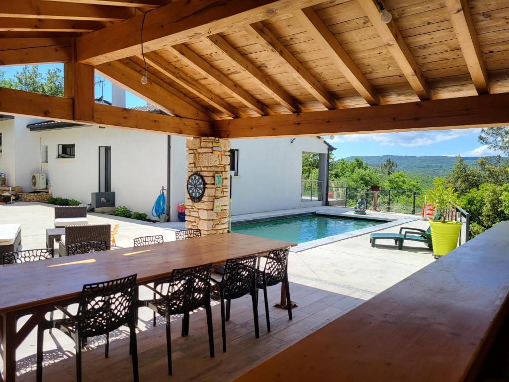 un patio avec une table et des chaises et une piscine dans l'établissement Villa contemporaine tout confort, à Saint-Julien-de-Peyrolas