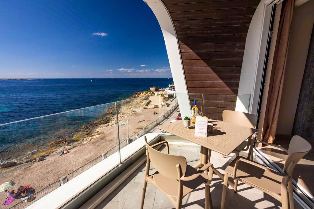a balcony with a table and chairs and a view of the ocean at Bugibba - Central Luxury Seafront, only for family in St. Paul's Bay