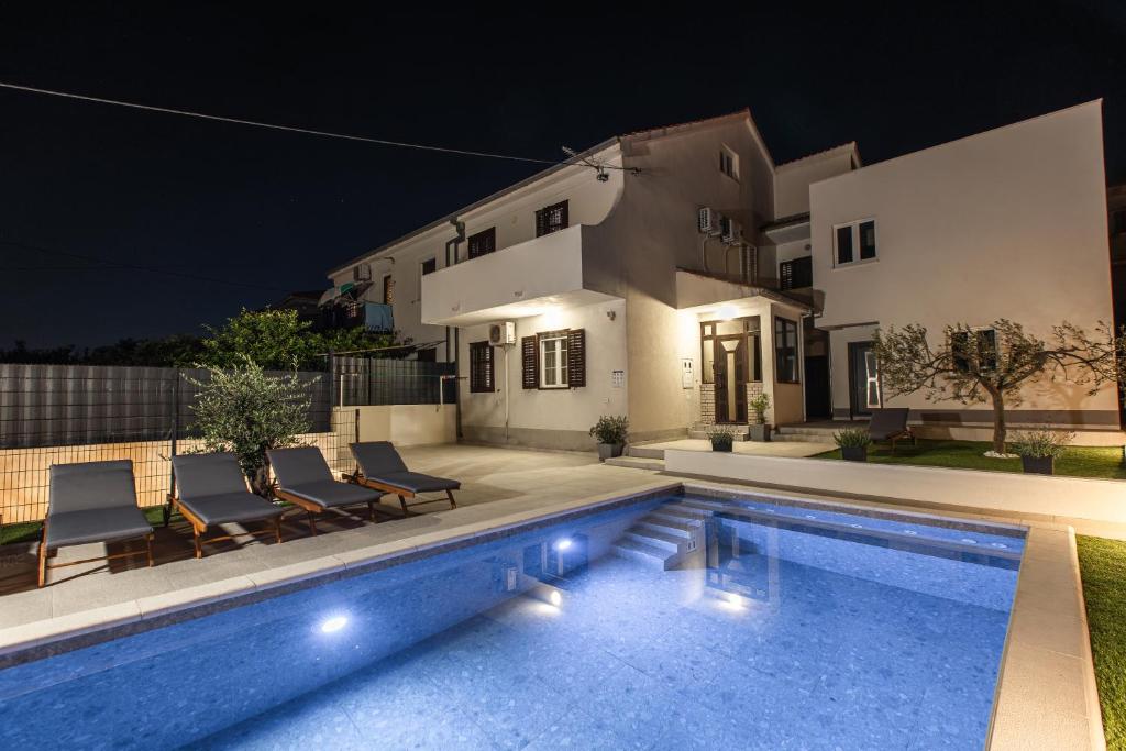 a swimming pool in front of a house at night at Poolhouse Domus in Solin