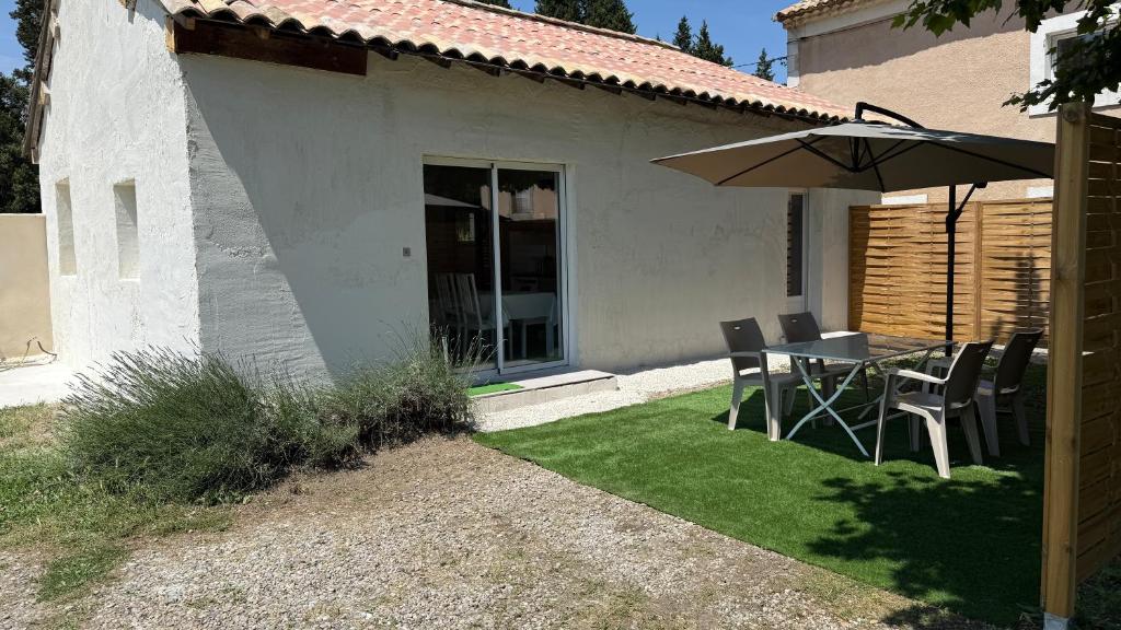 un patio avec un parasol, une table et des chaises dans l'établissement Maison indépendante dans mas Provençal, à Avignon