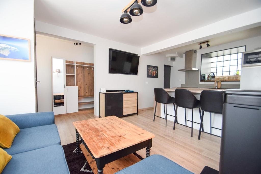 un salon avec un canapé bleu et une cuisine dans l'établissement Maison 4 pers cosy avec terrasse et Wifi, à Langrolay