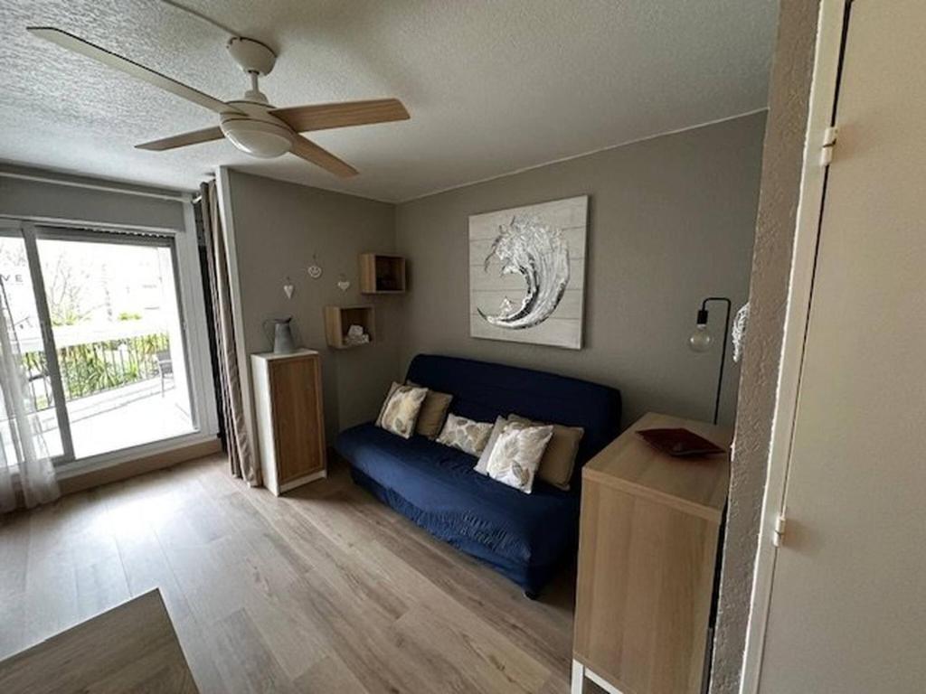 - un salon avec un canapé bleu et un ventilateur de plafond dans l'établissement Au couchant, studio pour 4 adultes et 1 enfant N69, à La Grande Motte
