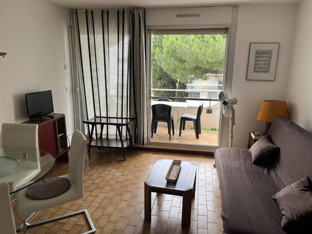 un salon avec un canapé et une table avec des chaises dans l'établissement Au centre ville de la Grande Motte, à 200m de la plage N68, à La Grande Motte