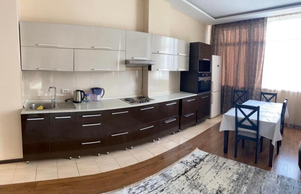 a kitchen with white cabinets and a table and a dining room at Жануя in Zhezdi