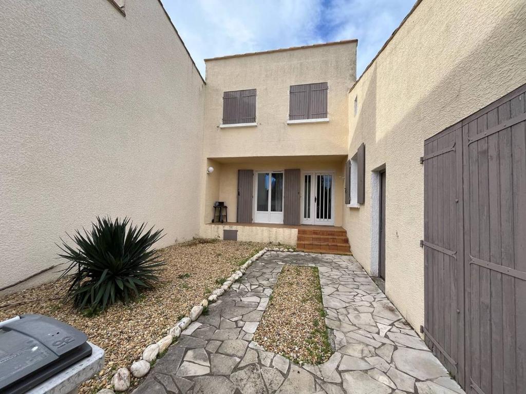 une maison avec une passerelle en pierre devant elle dans l'établissement Quartier des Goélands Villa t5 pour 8 personnes N25, à La Grande Motte