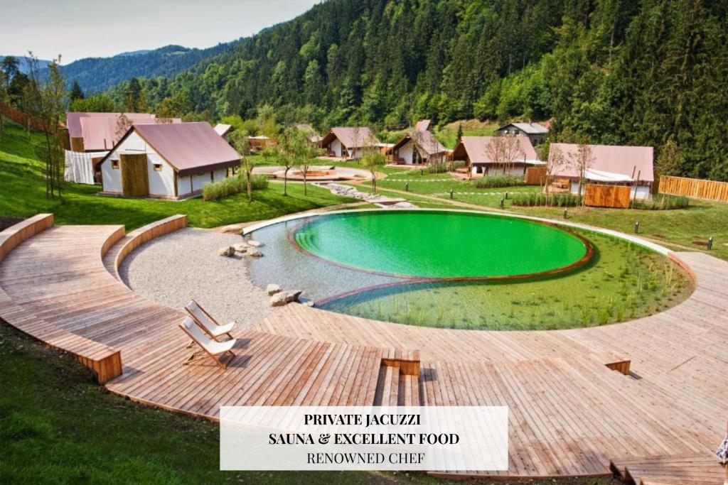 een zwembad met een houten terras naast een resort bij Herbal Glamping Resort Ljubno in Ljubno