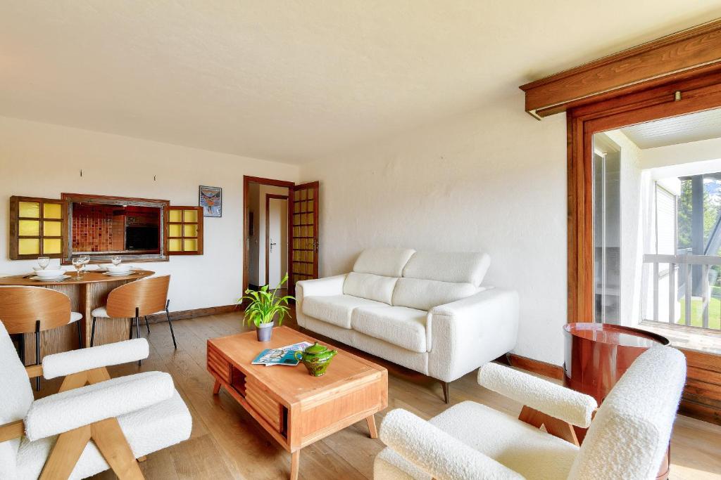 un salon avec des meubles blancs et une table dans l'établissement Appartement Mont d Arbois Megeve sur les pistes de ski, à Megève