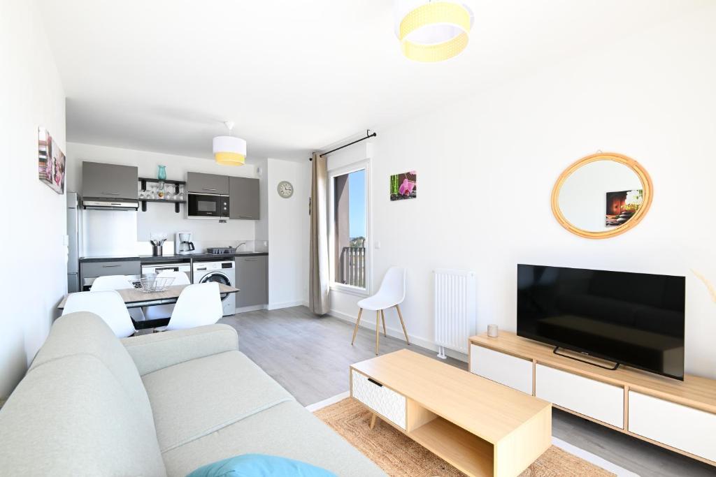 un salon avec un canapé et une télévision dans l'établissement Le Coquillage - Joli T3 avec grand balcon, à Courseulles-sur-Mer