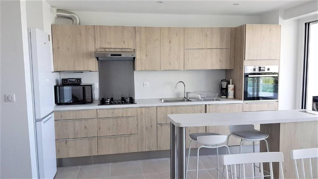 une cuisine avec des armoires en bois et un comptoir avec des tabourets dans l'établissement Coeur Plage et commerces Appartement type 3 pour 6 personnes N33, à La Grande Motte