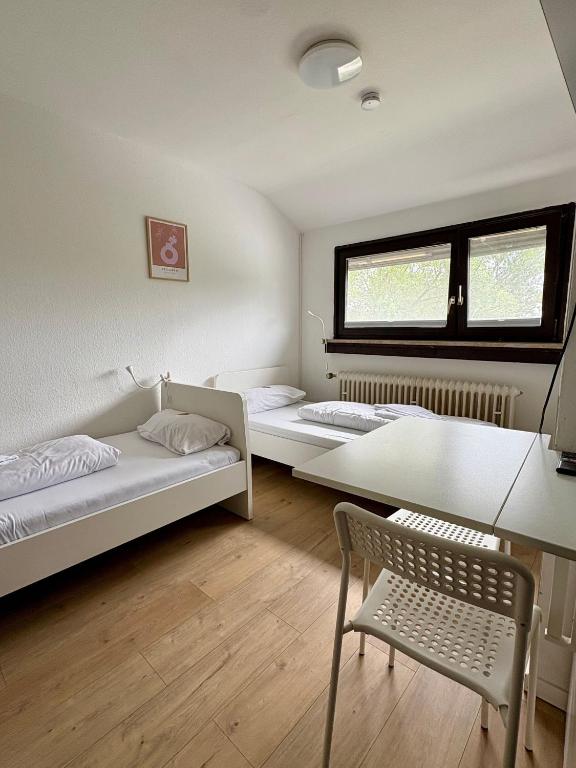 2 camas en una habitación con silla y mesa en kleine und charmante Monteurs Unterkunft D, en Karlsruhe