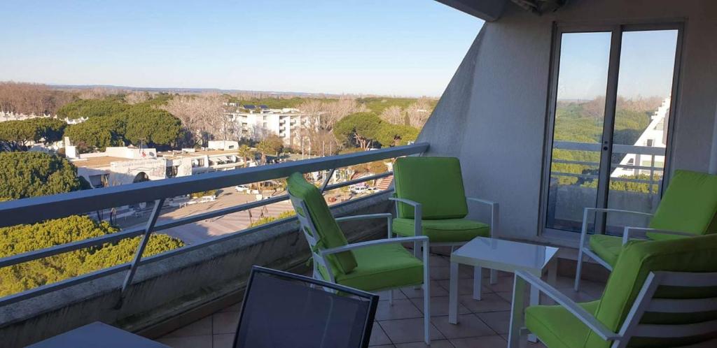 d'un balcon avec des chaises vertes et une vue sur la ville. dans l'établissement Coeur de ville avec piscine Appartement t4 pour 6 personnes N113, à La Grande Motte