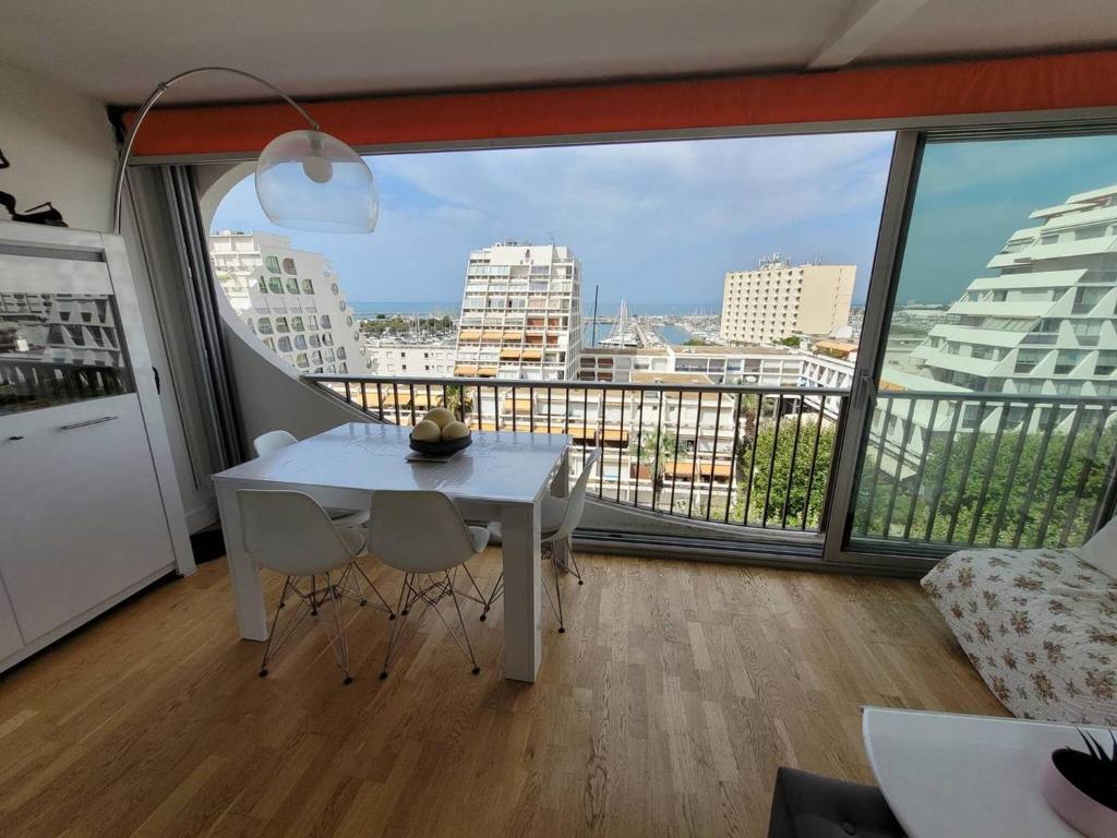 - une table et des chaises blanches dans une chambre dotée d'une grande fenêtre dans l'établissement Cœur de ville Appartement t2 cabine pour 4 personnes N127, à La Grande Motte