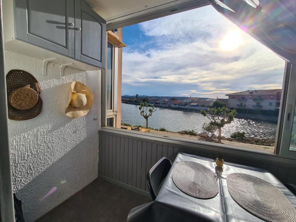 d'un balcon avec une table et une vue sur l'eau. dans l'établissement Le Nid du lac 600m des plages, à Port-la-Nouvelle