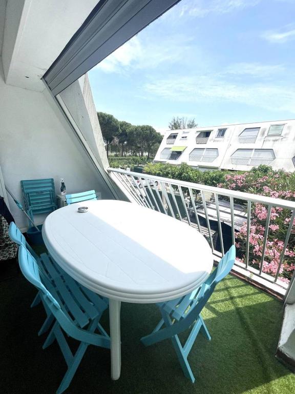 Il dispose d'un balcon avec une table et des chaises blanches. dans l'établissement Quartier couchant Appartement t2 cabine pour 5 personnes N106, à La Grande Motte
