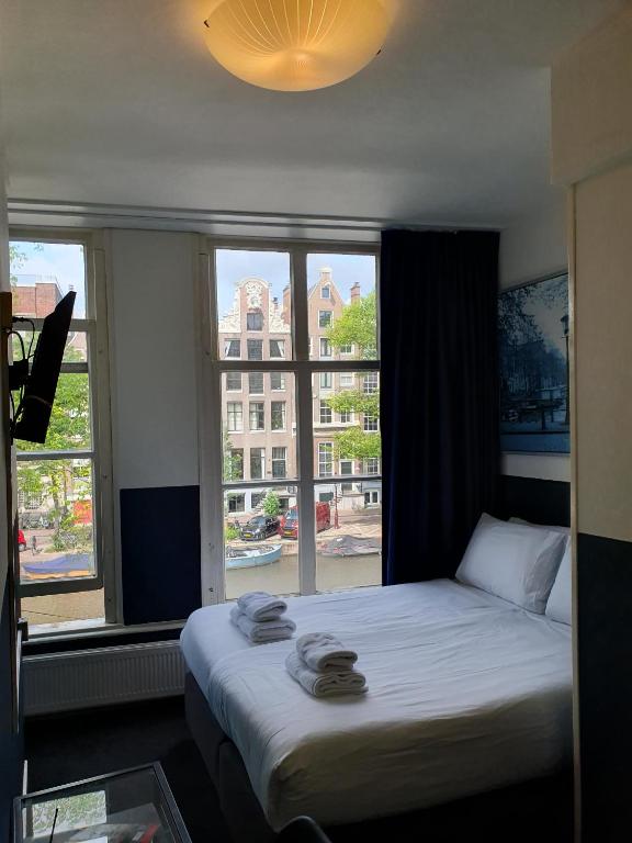 ein Bett in einem Zimmer mit einem großen Fenster in der Unterkunft Hotel Hoksbergen in Amsterdam