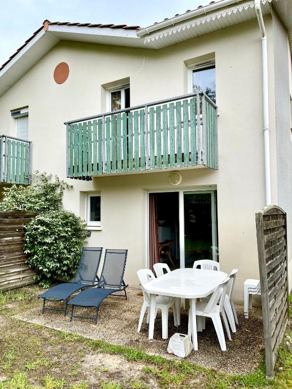 un patio avec une table et des chaises devant une maison dans l'établissement Villa Naiades, à Soulac-sur-Mer