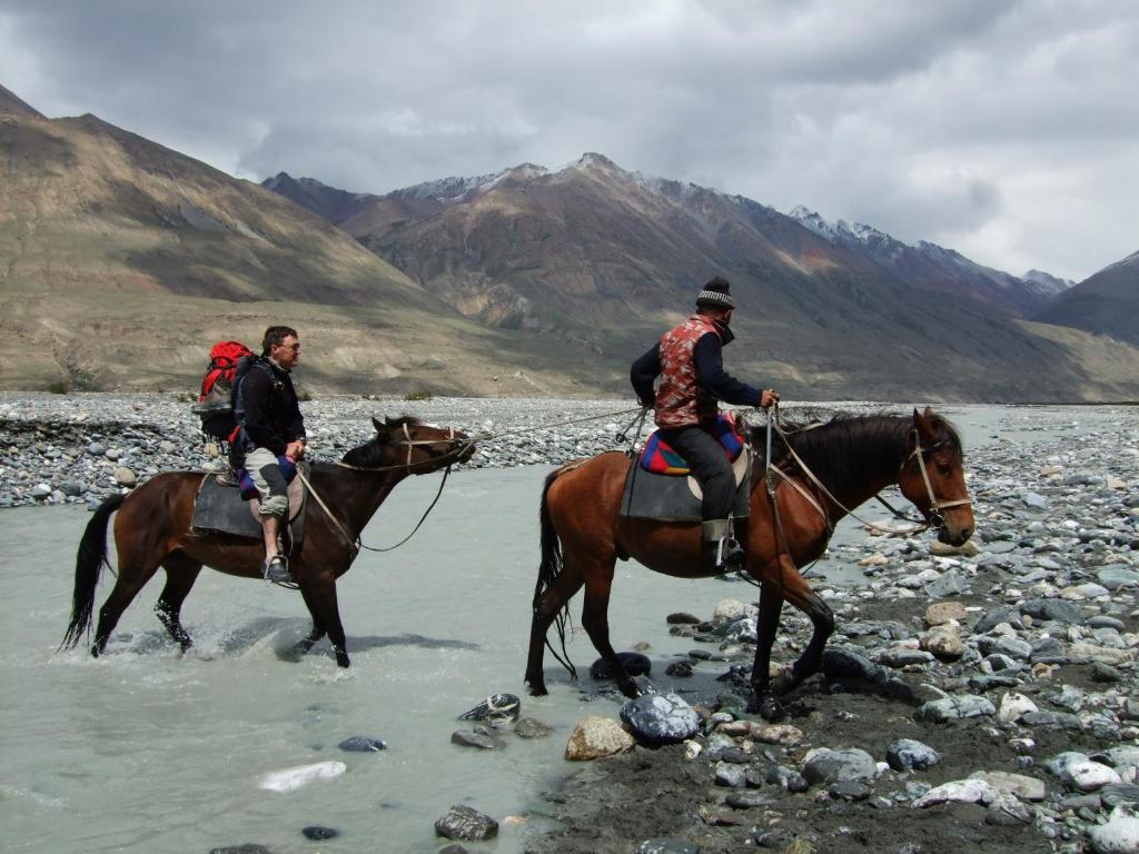 zwei Menschen reiten Pferde im Wasser in den Bergen in der Unterkunft City guesthouse & tours in Ulaanbaatar