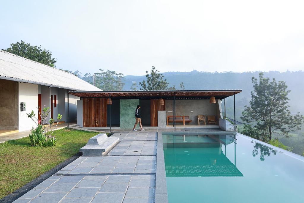 a man walking past a house with a swimming pool at VAASTA Vagamon in Vagamon