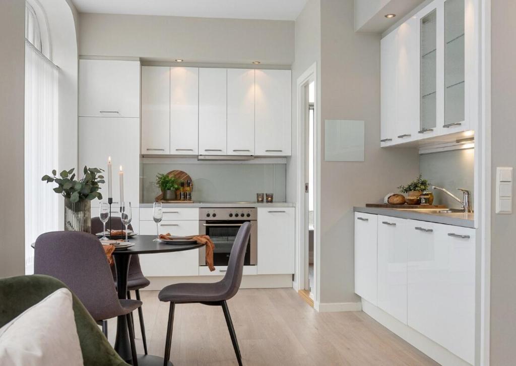 a kitchen with white cabinets and a table with chairs at Attractive and central apartment in Ålesund