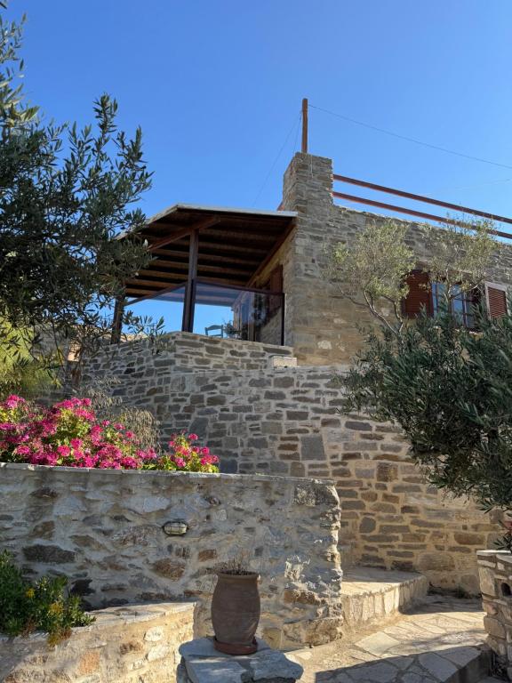 un edificio in pietra con finestra e alcuni fiori di Villa Kostopoulos Studio Zeus a Kampos Paros
