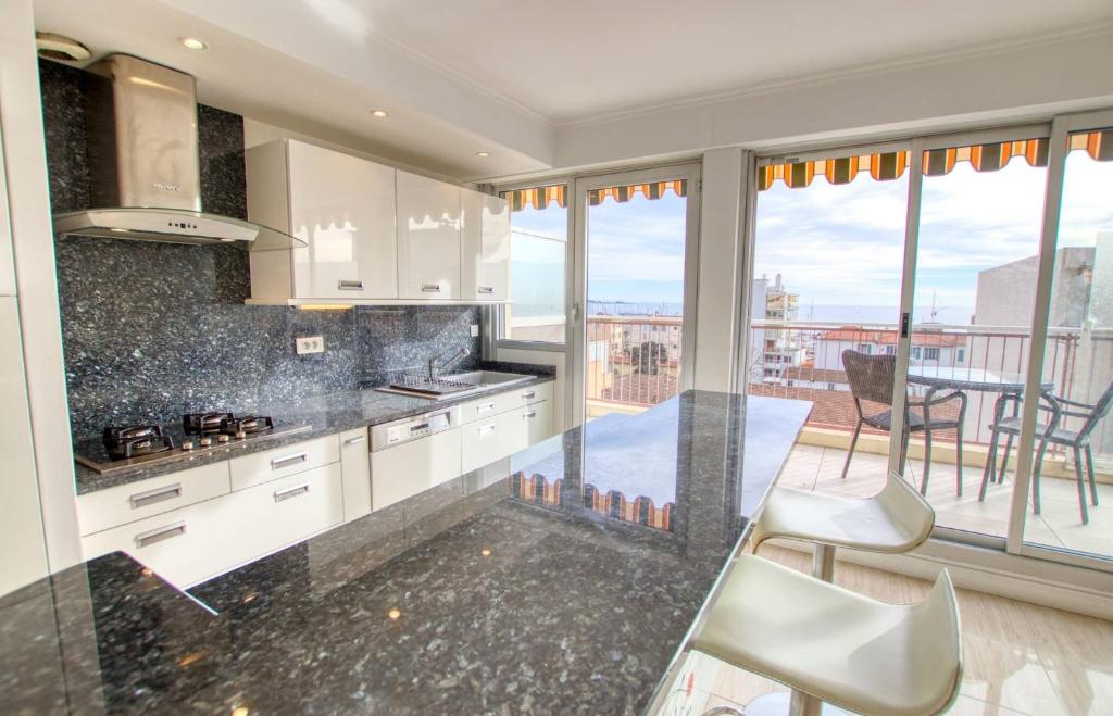 a kitchen with white cabinets and a large window at Le Clair Golfe-Juan - T2 terrasse vue mer Parking privé WIFI - LIMESTAY in Golfe-Juan